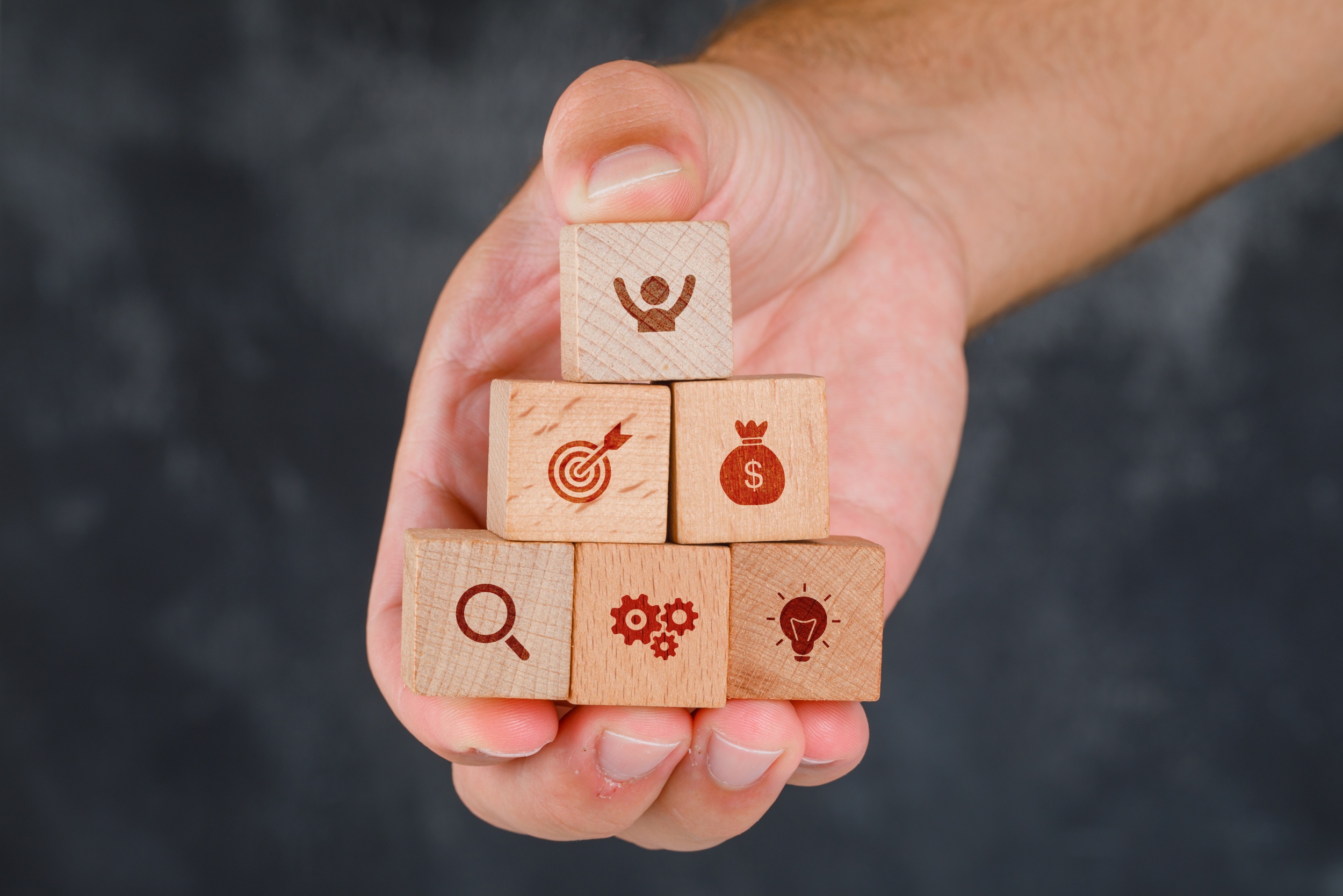Business concept on grungy grey background side view. hand holding wooden blocks with icons. Business concept on grungy grey background side view. hand holding wooden blocks with icons.