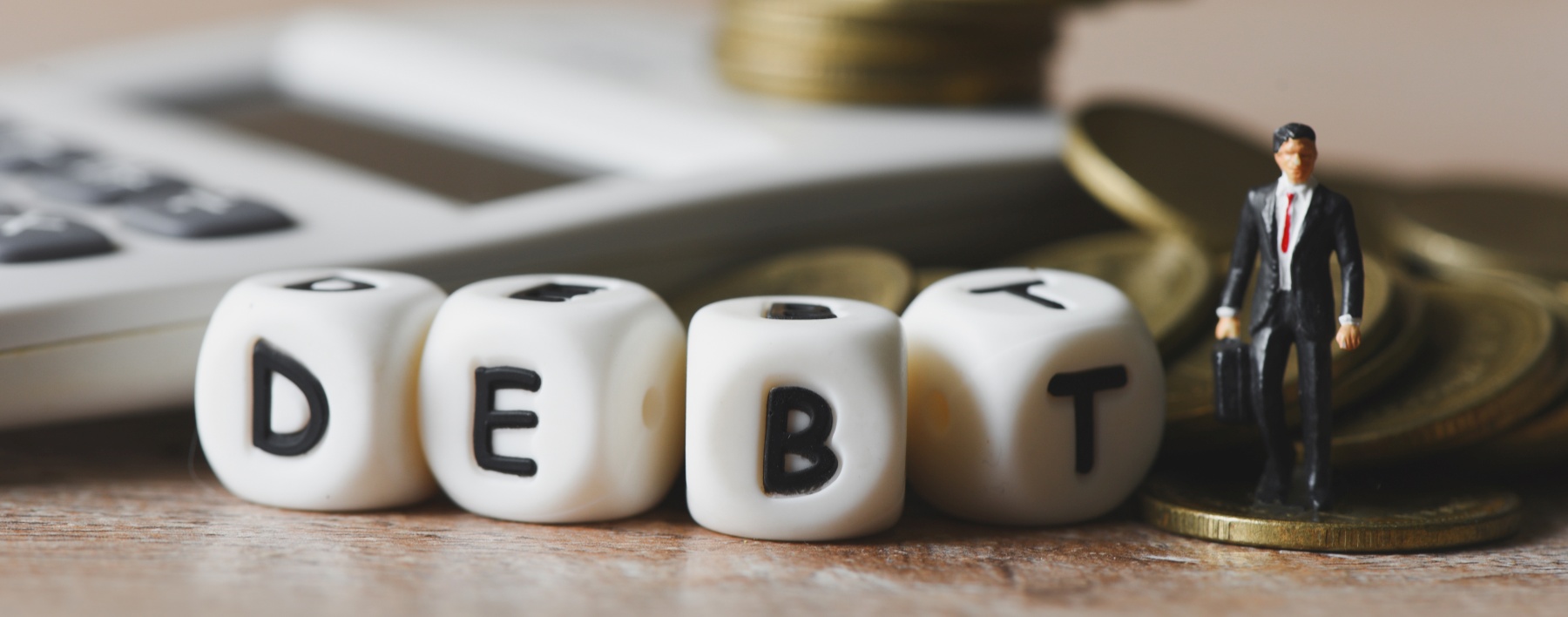 Block word debt on pile of coins and calculator with business ma Block word debt on pile of coins and calculator with business ma
